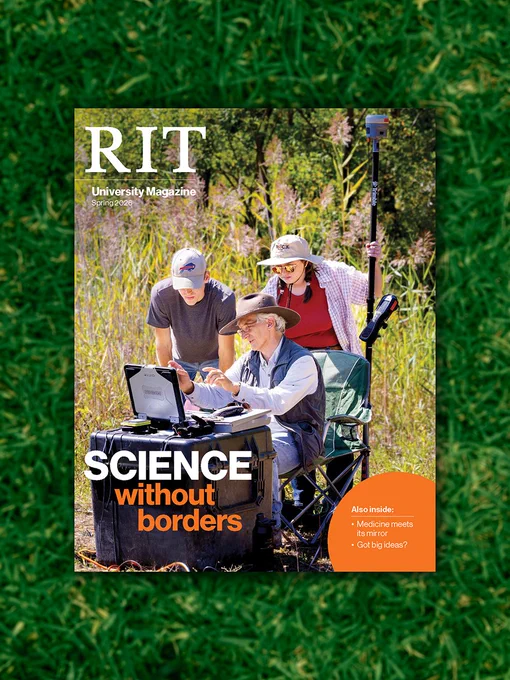 A magazine on a grass lawn. The cover of the magazine features two students and a professor using a screen and technology for research in a field. Text reads: R I T university magazine, spring 2026, Science without borders, also inside medicine meets its mirror and Got big ideas.