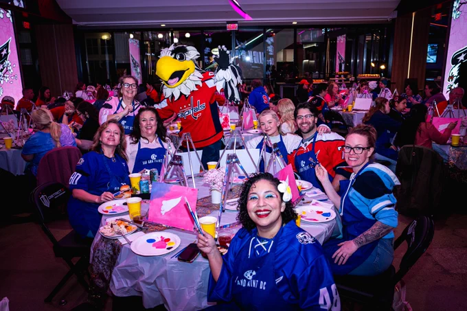 Caps fans smile while posting for a photo in front of their cherry blossom-themed paintings.
