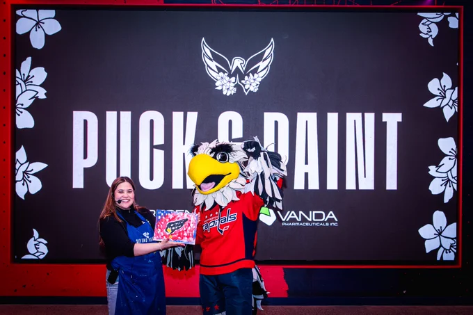 Slapshot poses for a picture with his artwork at the Puck & Paint event, presented by Vanda Pharmaceuticals.