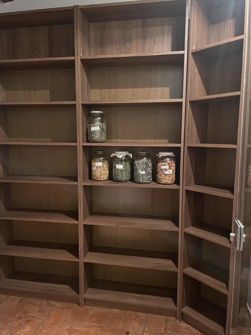 brown wood shelves with shoem large glass jars of herbs