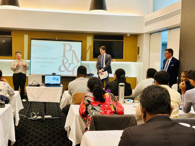 Presenter standing at the front of the room presenting to participants. 