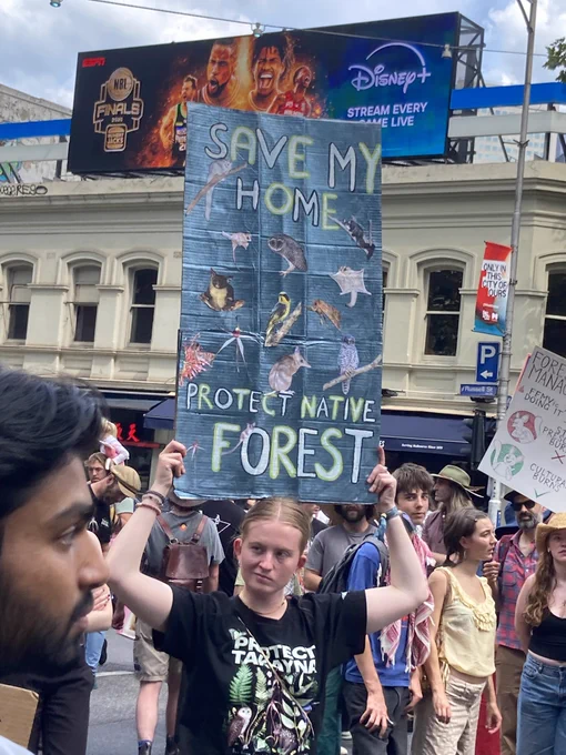 A girl holding a sign saying save my home, protect native forest” with Australian animals