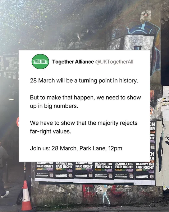 An image featuring a white text box overlaid on a photo of an urban street scene. The text box displays a social media post from "Together Alliance (@UKTogetherAll)" which reads: "28 March will be a turning point in history. But to make that happen, we need to show up in big numbers. We have to show that the majority rejects far-right values. Join us: 28 March, Park Lane, 12pm."

The background shows a concrete wall under a bridge or overpass, covered in graffiti and a row of black and white posters that mirror the message in the text box. The posters say "AGAINST THE FAR RIGHT" and include the date, time, and location: "28 MARCH 12PM PARK LANE, LONDON." A traffic cone is visible in the lower-left corner.