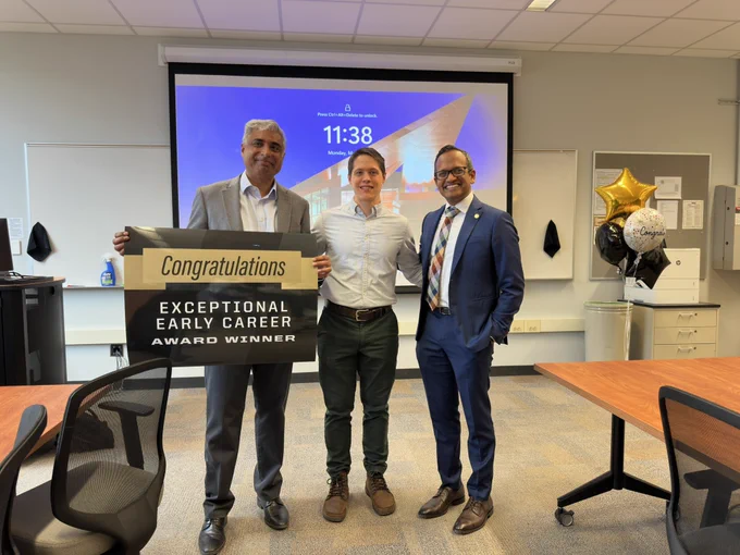 James Davis smiling for a picture in his classroom where he is being congratulated for the Exceptional Early Career award.