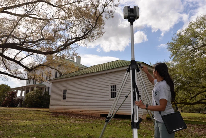 A woman uses equipment to scan a historic building