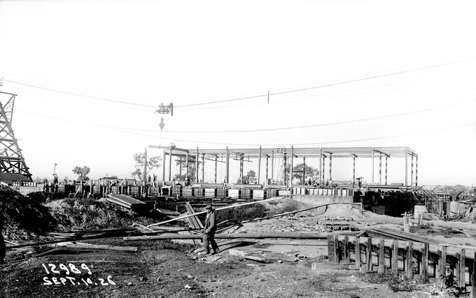Black and white historical photograph showing the construction of the Grit Building at the O'Brien Water Reclamation Plant on September 10, 1926. The image features a partially constructed building framework with workers and machinery present. Surrounding the site are construction materials and equipment, with power lines visible in the background. The date "SEPT. 10, 26" is marked in the lower left corner.