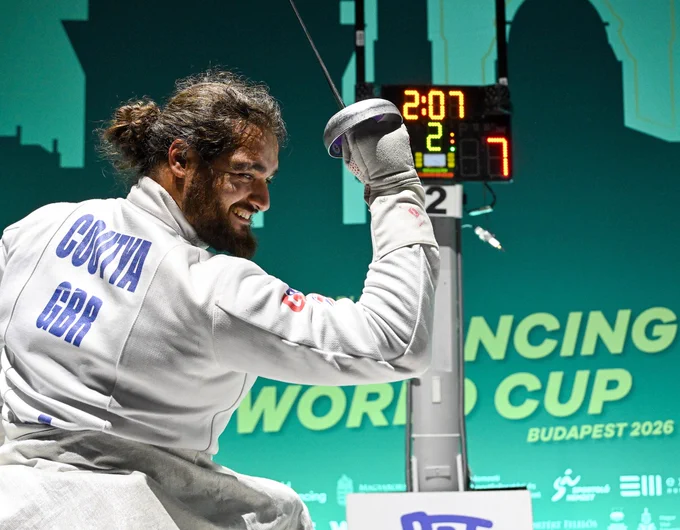 A GBR para epee fencer smiles and salutes after a win.