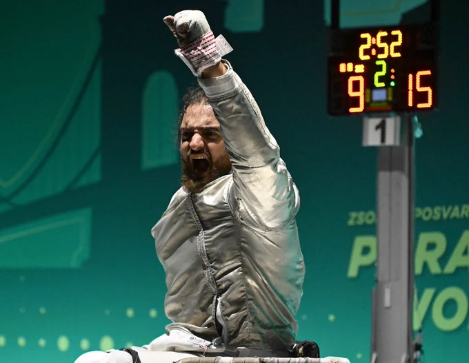 A GBR sabre para fencer raises his fist in victory.