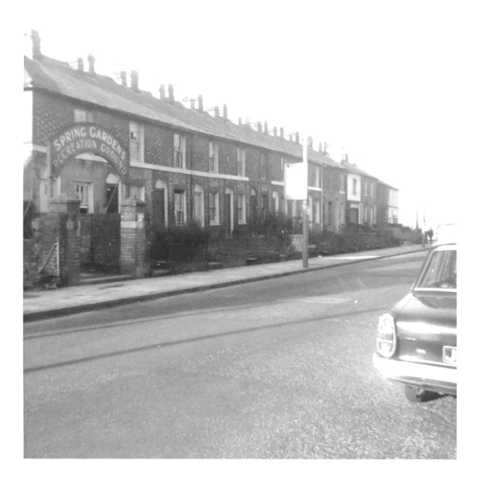 Black and white photo of Whitley Street, Reading, looking north. On the left is the entrance to Spring Gardens Recreation Ground, next to a row of terraced houses. The buildings have since been demolished.