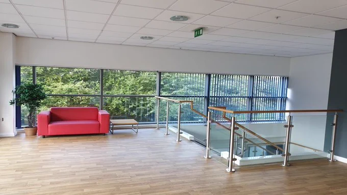 First floor area with steps leading down and a red sofa beside full length windows.