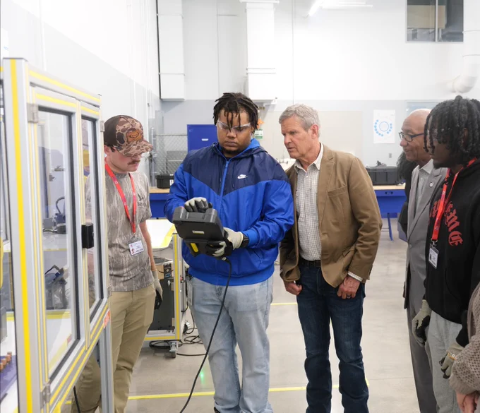 Governor Lee is watching students work in an advanced manufacturing lab.