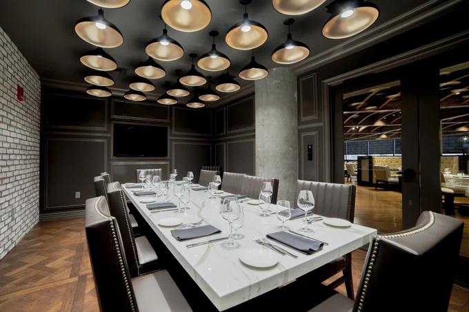 Tony's of Indianapolis's private dining space with long rectangular table fully set with glass doors and industrial overhead lighting