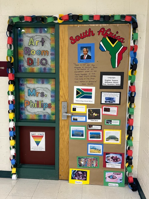 Classroom door decorated with South African theme, including flag, map, photos, and cultural facts, framed by colorful paper chain links.