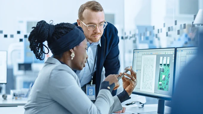 Female Supervisor Talks to a Male Electrical Engineer who Works on Computer with CAD Software.