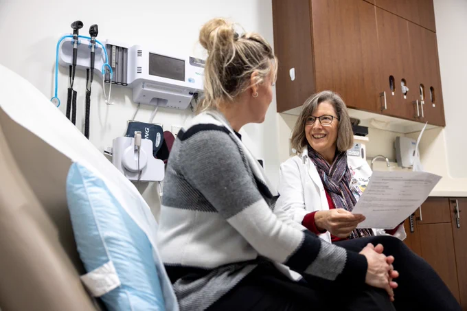 Clinician reviews paperwork with a seated patient in a clinic exam room