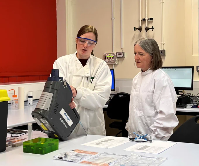 Drugs and Alcohol Policy Minister Maree Todd and a Leverhulme Research Centre for Forensic Science staff member wearing white lab coats, looking at equipment in a laboratory.  
