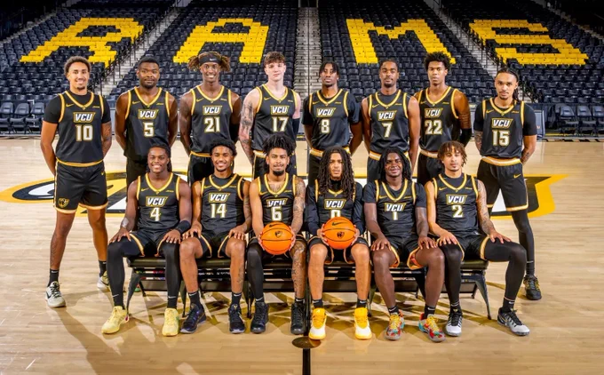 Group shot of the V-C-U men's basketball team at the Siegel Center. The front row of players sit on chairs while the back row stands.