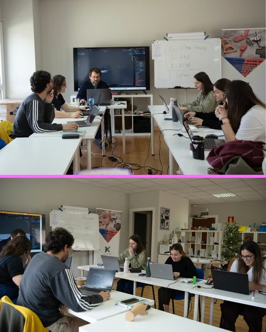 Grupo de personas trabajando con ordenadores portátiles en un aula, con una pantalla grande mostrando un software de diseño 3D y una pizarra con anotaciones.