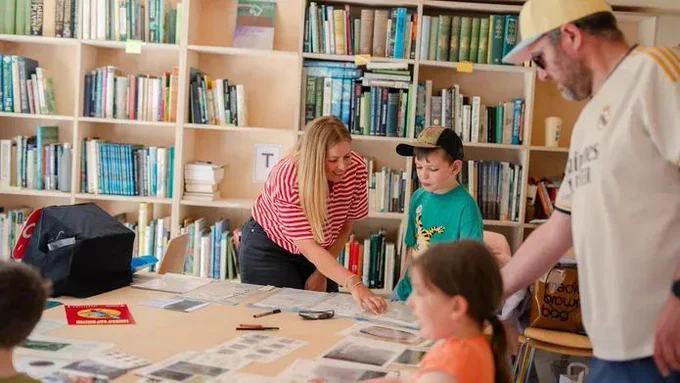 Photograph of a women guiding two young children through a forensic science activity were they compare multiple sets of footwear marks.