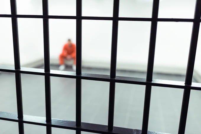Man in orange clothing inside an empty jail room
