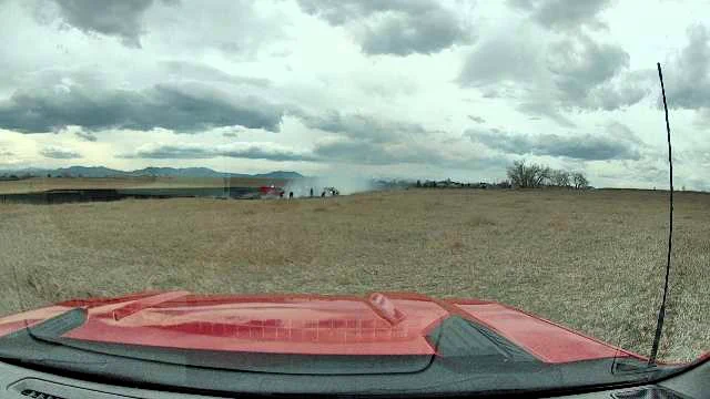 Firefighters working in a dry field with burn area and smoke