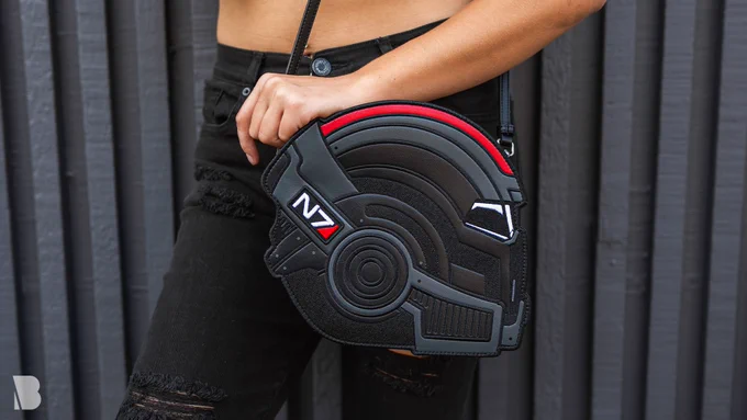 The Mass Effect N7 Helmet Crossbody Bag, feat. a printed and embroidered N7 helmet on the front, and a debossed Specter emblem on the back.