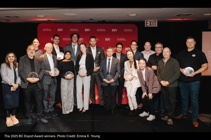 Participants at the BC Export Awards standing on stage in front of a red backdrop, holding awards and smiling. Photo Credit: Emma K. Young