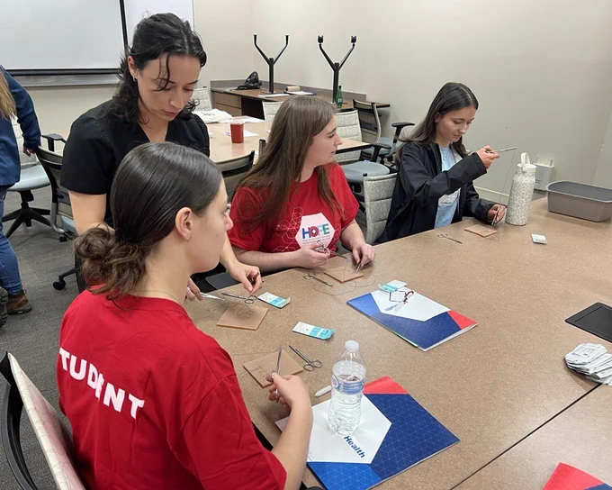 A volunteer teaches suturing skills to students