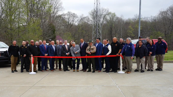TACN and Montgomery County leaders are cutting a ribbon with oversized scissors in front of the new radio tower.