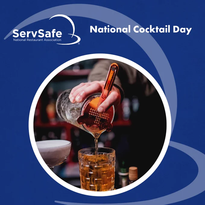 Bartender pouring a cocktail through a strainer into a glass, surrounded by bottles. The image features a "ServSafe National Restaurant Association" logo and text reading "National Cocktail Day" on a blue background.