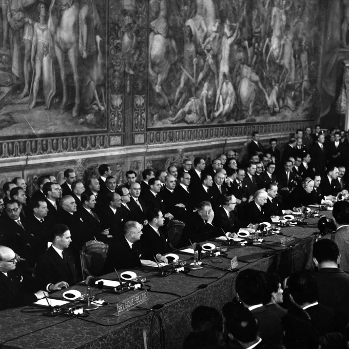 General high up view of delegates from the six European Nations seated during the signing ceremony: In the front row from left to right, the signatories, for Belgium, Paul-Henri Spaak, Jean-Charles Snoy et d’Oppuers, for France, Christian Pineau, Maurice Faure, for Germany, Konrad Adenauer, Walter Hallstein, for Italy, Antonio Segni et Gaetano Martino, for Luxembourg, Joseph Bech, Lambert Schaus, and for the Netherlands, Joseph Luns and Johannes Linthorst-Homan 