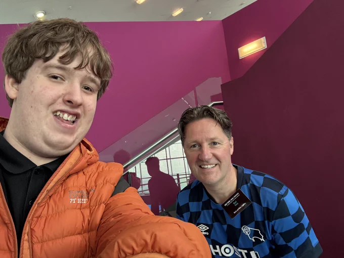 Jack and Nigel at the Fair Game Annual Conference. Jack takes the selfie, wearing an Orange coat. Nigel is sporting the blue checkered Derby shirt from the 2023-24 season.
