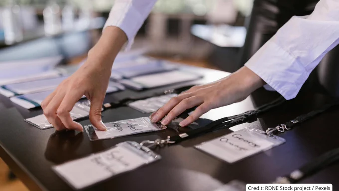 Person arranging name badges on a table, preparing for an event or conference setup.