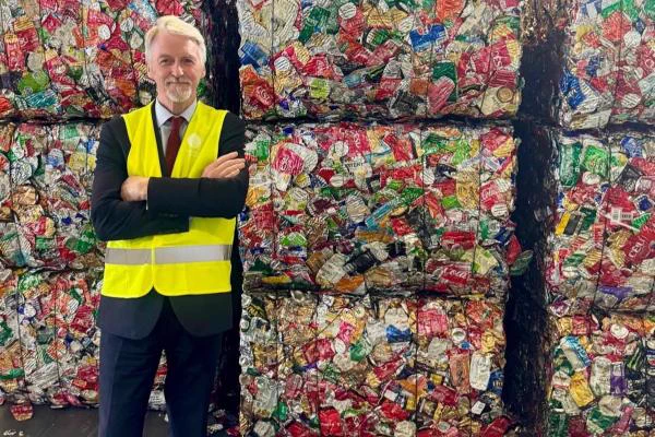 Deputy First Minister in front of compressed recyclable cans.