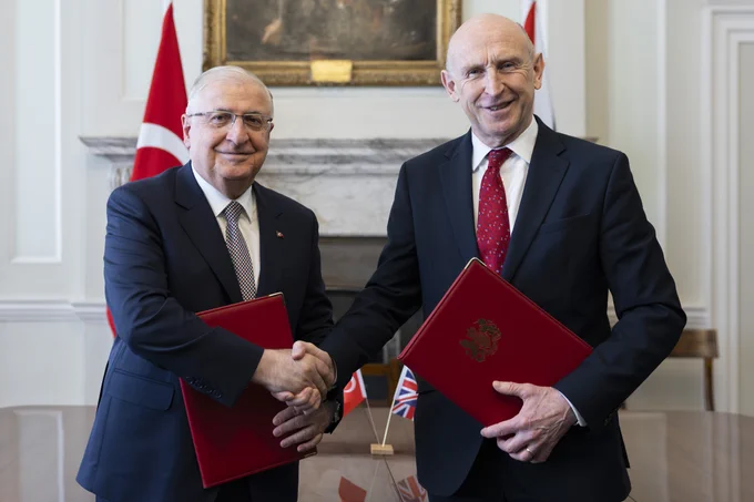 The Secretary of State for Defence John Healey (r) and Türkiye’s Minister of National Defence Yaşar Güler shake hands while holding dossiers.