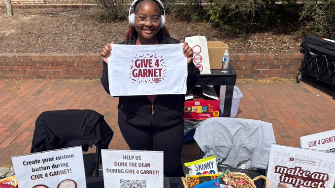 A student holds up a Give 4 Garnet towel