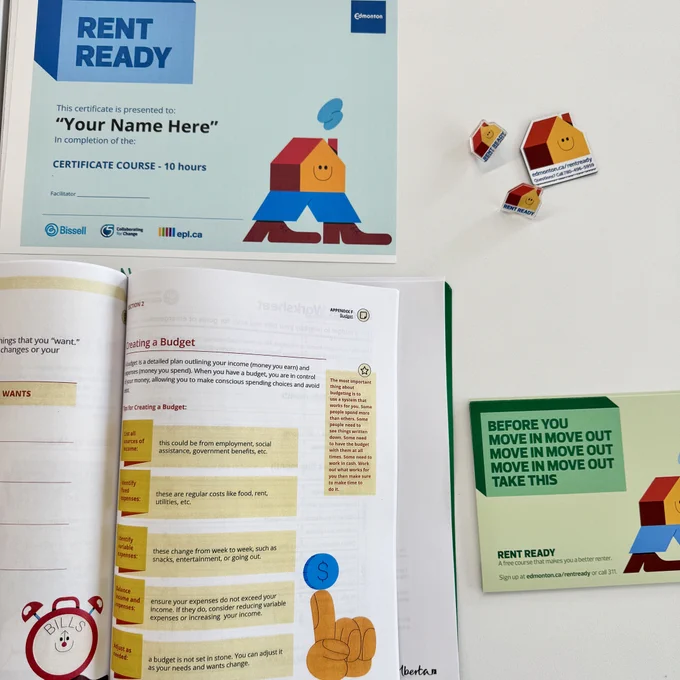 A Rent Ready booklet, certificate, postcard, pins and magnets sit on a table.