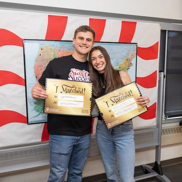 male and female holding gold placards