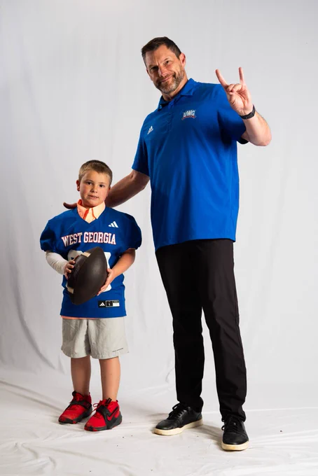 Maddox posing in front of a white backdrop with head Coach Steve Englehart