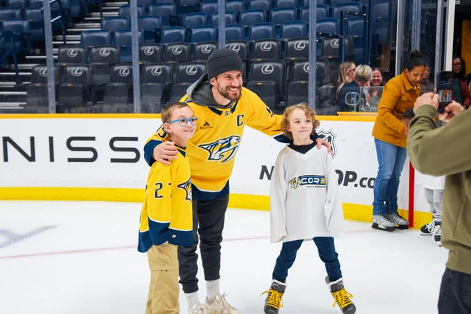 Image of Roman Josi posing for a photo at the CORE skating event with a couple young skaters 