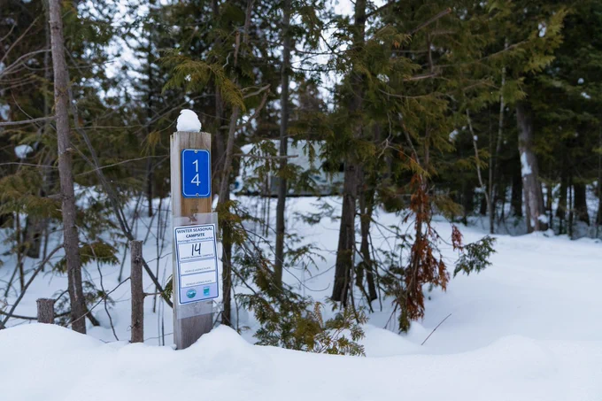 site post sign with card for winter seasonal site information, the wooden site post is surrounded by snow. 