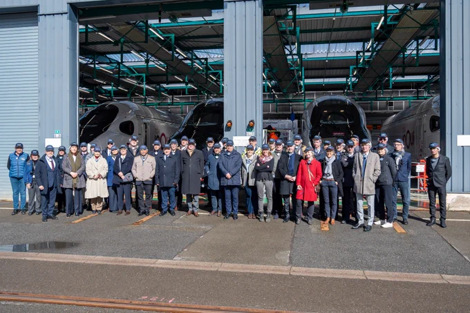 Les membres du CAR posent devant les ateliers d'Alstom. En arrière plan se dessinent les TGV du futur