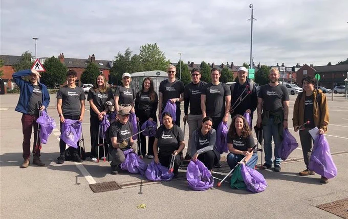 A group of volunteers with Litter Free Leeds purple bags in a car park in Harehills