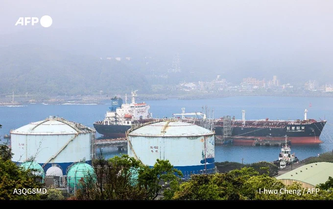 An oil products tanker sits in a harbour behind two small towers,with mist in the distance