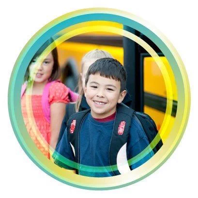 Smiling schoolchildren next to a school bus