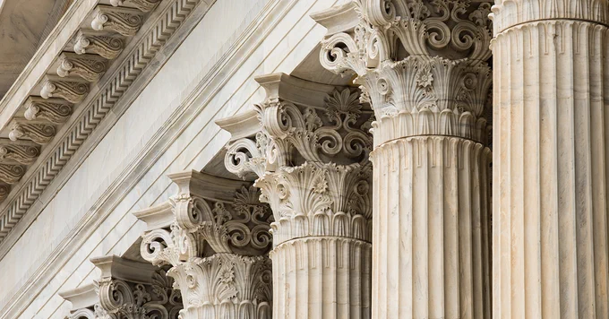 Row of ornate Corinthian columns with intricate capitals, possibly part of a historical or government building.