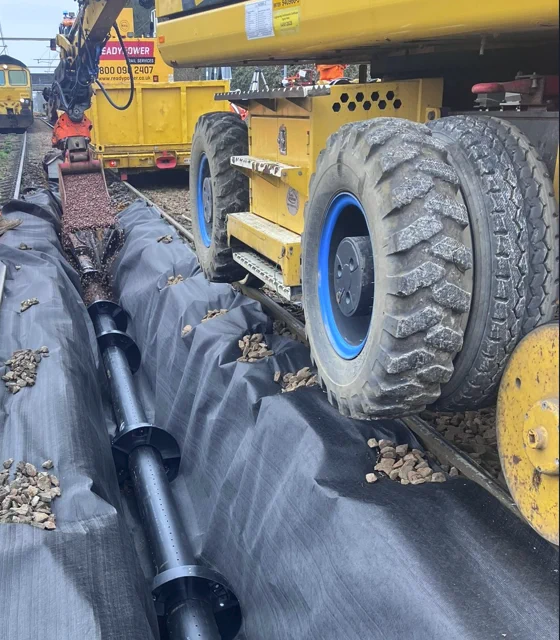 Slotted pipes visible, next to yellow plant