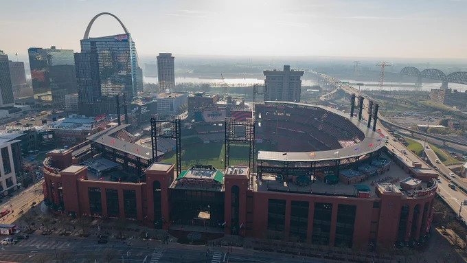 Aerial view of Busch Stadium in St. Louis. The St. Louis Arch and Mississippi River are visible in the background.