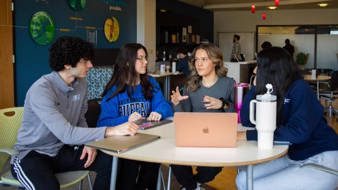 Four students sitting around a table, working together.