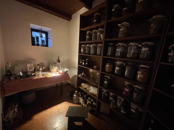 herb room with dark wood shelves filled with large glass jars and a small table 